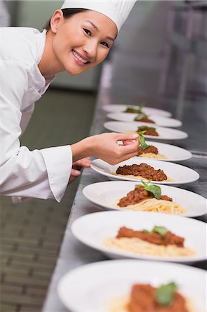 Happy chef putting basil leaf on spaghetti dish Foto de stock - Sin royalties Premium, Código: 6109-07601125