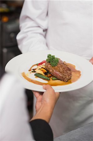 passing (from one to another) - Waitress taking steak dinner from chef Stock Photo - Premium Royalty-Free, Code: 6109-07601137