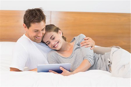 simsearch:6109-07497359,k - Happy couple on bed using tablet pc Fotografie stock - Premium Royalty-Free, Codice: 6109-07601258