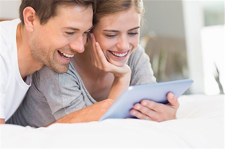 simsearch:6109-07601273,k - Happy couple on bed using tablet pc Stock Photo - Premium Royalty-Free, Code: 6109-07601259