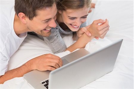 simsearch:6109-07601273,k - Happy couple on bed using laptop Stock Photo - Premium Royalty-Free, Code: 6109-07601261