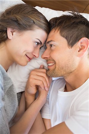 simsearch:6109-07601273,k - Happy couple lying on bed holding hands Stock Photo - Premium Royalty-Free, Code: 6109-07601273