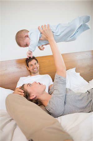 simsearch:6109-08536469,k - Happy parents relaxing on bed with their baby son Stock Photo - Premium Royalty-Free, Code: 6109-07601284