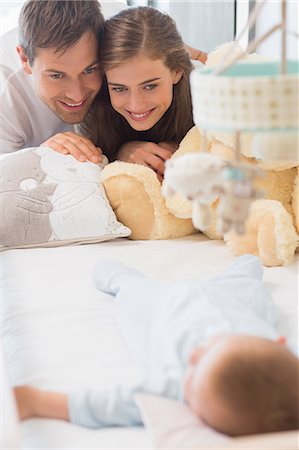 simsearch:6109-07601273,k - Happy parents watching over baby son sleeping in crib Stock Photo - Premium Royalty-Free, Code: 6109-07601289