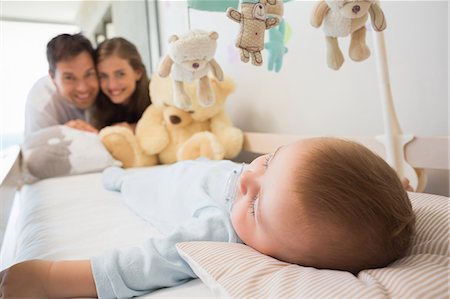 simsearch:6109-07601273,k - Happy parents watching over baby son sleeping in crib Stock Photo - Premium Royalty-Free, Code: 6109-07601290
