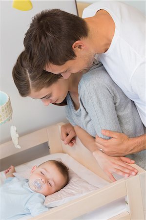 Happy parents watching over baby son in crib Stock Photo - Premium Royalty-Free, Code: 6109-07601295