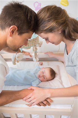 Happy parents watching over baby son in crib Stock Photo - Premium Royalty-Free, Code: 6109-07601299