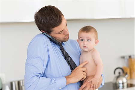 simsearch:6102-08858419,k - Busy father holding his baby son before work Stock Photo - Premium Royalty-Free, Code: 6109-07601350