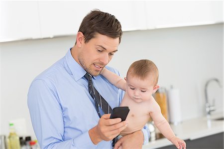simsearch:6102-08858419,k - Busy father holding his baby son before work Stock Photo - Premium Royalty-Free, Code: 6109-07601351