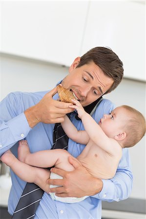 simsearch:614-01558935,k - Busy father holding his baby son before work and eating toast Foto de stock - Sin royalties Premium, Código: 6109-07601352