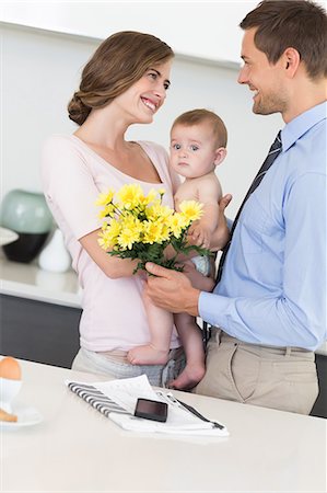 dad mom and children - Father giving mother holding baby a bunch of yellow flowers Stock Photo - Premium Royalty-Free, Code: 6109-07601358