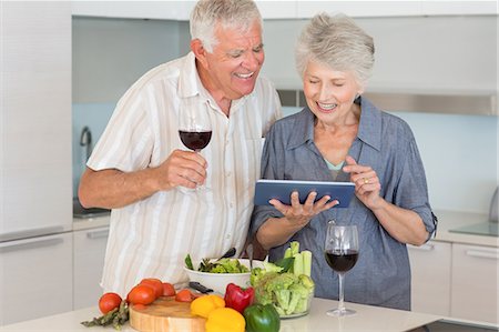 simsearch:6109-07601417,k - Smiling senior couple preparing a salad and using tablet pc Foto de stock - Sin royalties Premium, Código: 6109-07601378