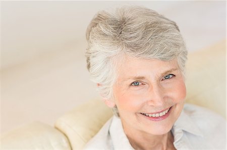 simsearch:6109-07601473,k - Senior woman sitting on couch smiling at camera Stock Photo - Premium Royalty-Free, Code: 6109-07601450