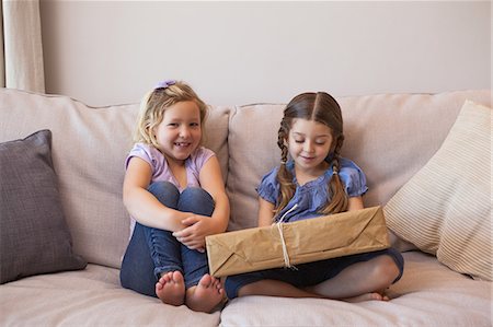 Young girls sitting with gift box on couch Photographie de stock - Premium Libres de Droits, Code: 6109-07601492