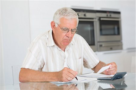 papers flat on table - Focused senior man paying his bills Stock Photo - Premium Royalty-Free, Code: 6109-07601415