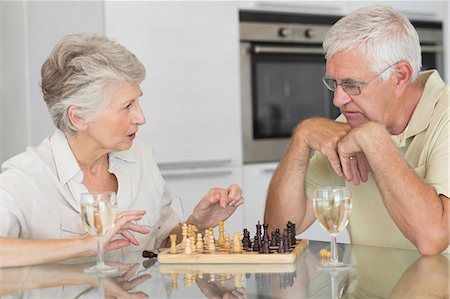 elderly couple in home - Smiling senior couple playing chess and having white wine Photographie de stock - Premium Libres de Droits, Code: 6109-07601423