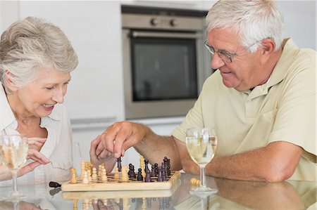 Smiling senior couple playing chess and having white wine Foto de stock - Sin royalties Premium, Código: 6109-07601424