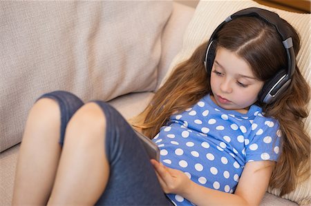 Girl listening music while using digital tablet in the living room Stock Photo - Premium Royalty-Free, Code: 6109-07601514