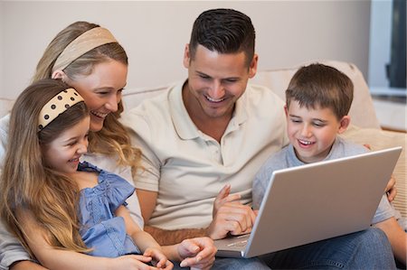 simsearch:6109-08953075,k - Happy family of four using laptop in living room Fotografie stock - Premium Royalty-Free, Codice: 6109-07601518