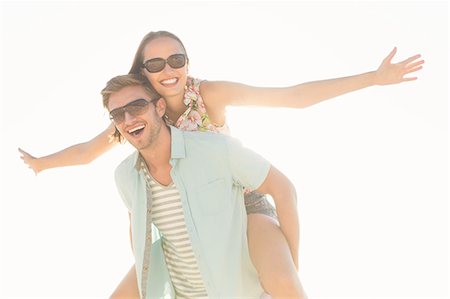 simsearch:6109-08489781,k - Handsome man giving piggy back to his girlfriend looking at camera Stock Photo - Premium Royalty-Free, Code: 6109-08203038
