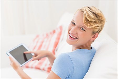 simsearch:6109-08390544,k - Portrait of smiling woman sitting on couch and using tablet computer Stock Photo - Premium Royalty-Free, Code: 6109-08203473