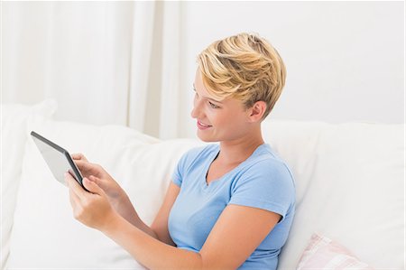 simsearch:6109-08390544,k - Smiling woman sitting on couch and using tablet computer Stock Photo - Premium Royalty-Free, Code: 6109-08203472