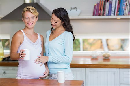 flat tummy women - Lesbian woman touching her pregnant girlfriend stomach Stock Photo - Premium Royalty-Free, Code: 6109-08203409