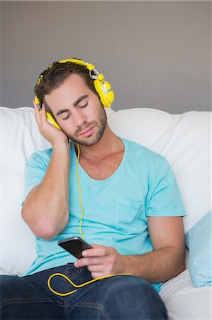simsearch:6109-08582007,k - Relaxed handsome man listening music with headphones on couch Fotografie stock - Premium Royalty-Free, Codice: 6109-08203775