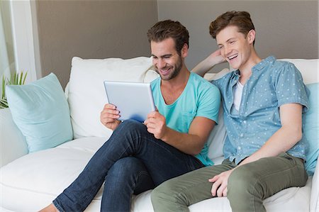 simsearch:6109-08390086,k - Cute homosexual couple looking at tablet on couch Foto de stock - Sin royalties Premium, Código: 6109-08203781