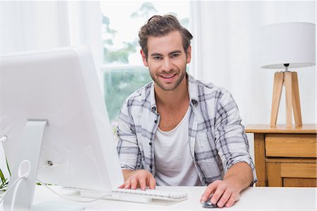 Happy handsome man using computer and looking at camera Stock Photo - Premium Royalty-Free, Code: 6109-08203733