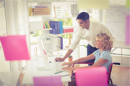 Young smiling businesswoman in a wheelchair getting help from a businessman Foto de stock - Sin royalties Premium, Código: 6109-08203956