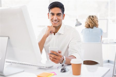 designer (male) - Young smiling businessman in the office holding a mobile Foto de stock - Sin royalties Premium, Código: 6109-08203974