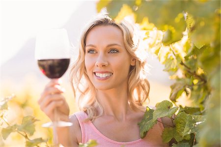 Smiling woman looking at wineglass standing next to grapevine Photographie de stock - Premium Libres de Droits, Code: 6109-08203997