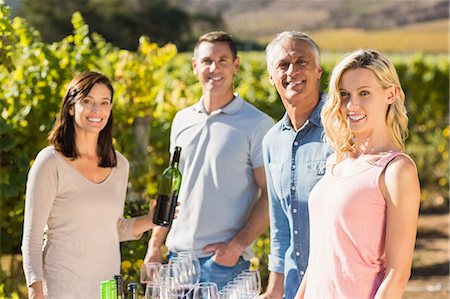 Portrait of smiling sommelier holding wine bottle and her customers Stock Photo - Premium Royalty-Free, Code: 6109-08204009