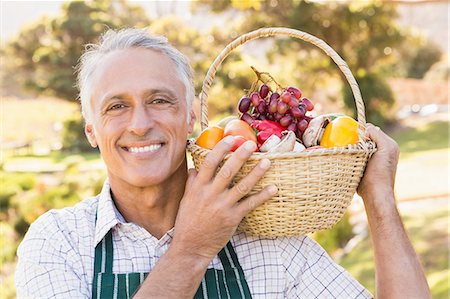 simsearch:6109-08204305,k - Mature happy farmer holding a basket of vegetables Stock Photo - Premium Royalty-Free, Code: 6109-08204292