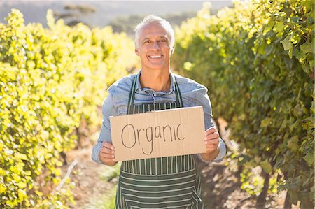simsearch:6109-08204304,k - Smiling farmer holding an organic sign Photographie de stock - Premium Libres de Droits, Code: 6109-08204329