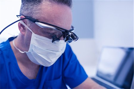 simsearch:6109-08389797,k - Concentrated male dentist with dental loupes Stock Photo - Premium Royalty-Free, Code: 6109-08389797