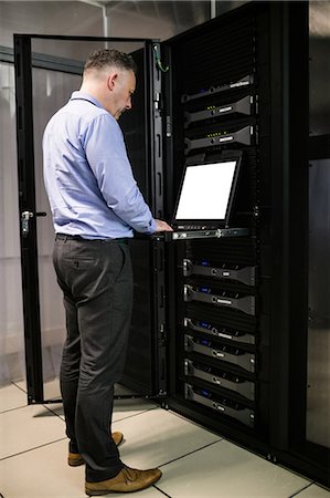 simsearch:6109-08389972,k - Technician using laptop in server room Stock Photo - Premium Royalty-Free, Code: 6109-08389957