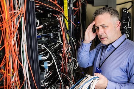 picture of man confused with cable - Stressed technician looking at open server locker Stock Photo - Premium Royalty-Free, Code: 6109-08389973