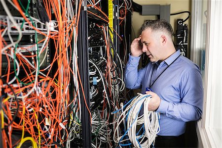 Stressed technician looking at open server locker Fotografie stock - Premium Royalty-Free, Codice: 6109-08389972