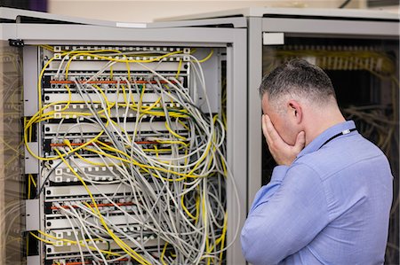 picture of man confused with cable - Stressed technician looking at open server locker Stock Photo - Premium Royalty-Free, Code: 6109-08389981