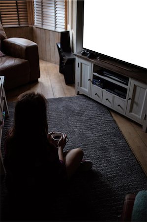 Young girl holding mug watching tv Photographie de stock - Premium Libres de Droits, Code: 6109-08390066