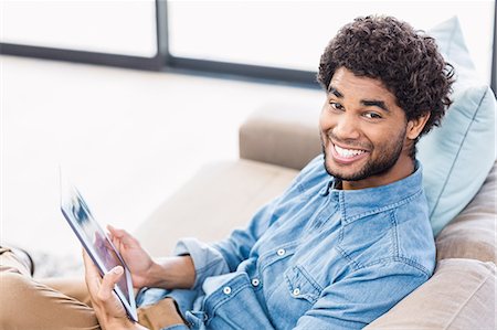 simsearch:6109-08390086,k - Handsome man holding tablet and smiling at the camera Foto de stock - Sin royalties Premium, Código: 6109-08390094