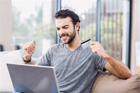 people cheering excite at home - Happy man holding credit card and using laptop Stock Photo - Premium Royalty-Free, Code: 6109-08390197