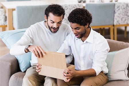 ethnic couples at home on sofa - Happy gay couple opening box Stock Photo - Premium Royalty-Free, Code: 6109-08390241