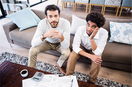 simsearch:6109-07601399,k - Worried gay couple with bills on table looking at camera Photographie de stock - Premium Libres de Droits, Code: 6109-08390204