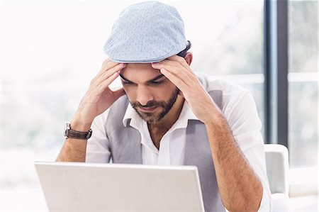 simsearch:6109-08203934,k - Worried man with hands on his face while looking at laptop Photographie de stock - Premium Libres de Droits, Code: 6109-08390322