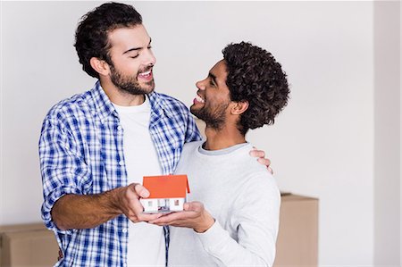 simsearch:6109-08390455,k - Happy gay couple holding miniature house model Fotografie stock - Premium Royalty-Free, Codice: 6109-08390467
