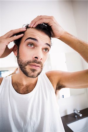 Concentrated man looking at his hair Stock Photo - Premium Royalty-Free, Code: 6109-08390437