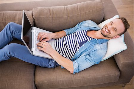 simsearch:6109-08581996,k - Handsome man using laptop on couch Fotografie stock - Premium Royalty-Free, Codice: 6109-08390585